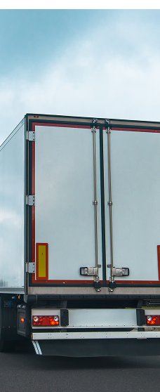 Rear view of a white cargo truck with closed doors on the road under a cloudy sky